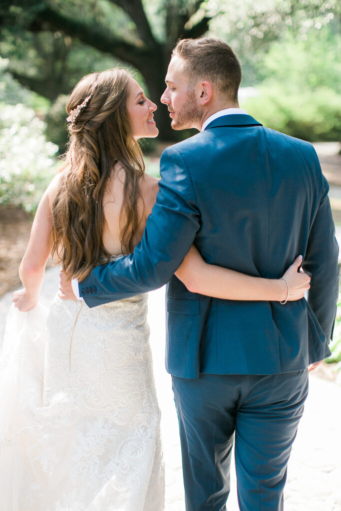 Bride and groom kiss as they walk in Airlie Gardens