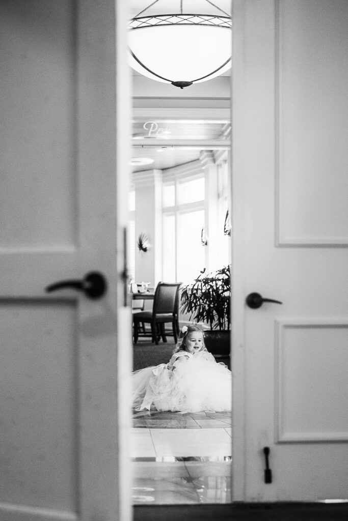 looking through a door, the flower girl waits for her part in the wedding on Bald Head Island.