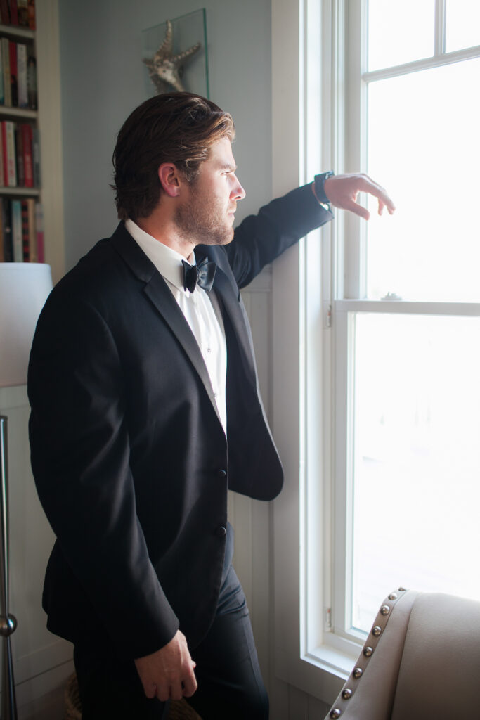 Groom looks out window before his wedding.