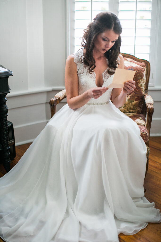 Bride sitting reading a letter from her groom on her wedding day.