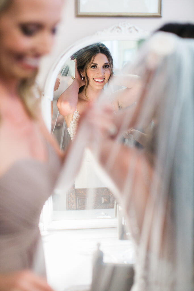 Bride getting ready in mirror before wedding.