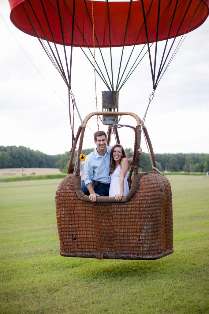 A hot air balloon engagement session in Wilmington NC.  The couple smiles for the camera as their balloon lifts off.