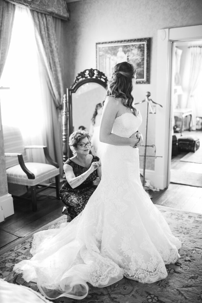 A mother helps a bride button her dress while getting ready at the City Club in Downtown Wilmington NC before her wedding.