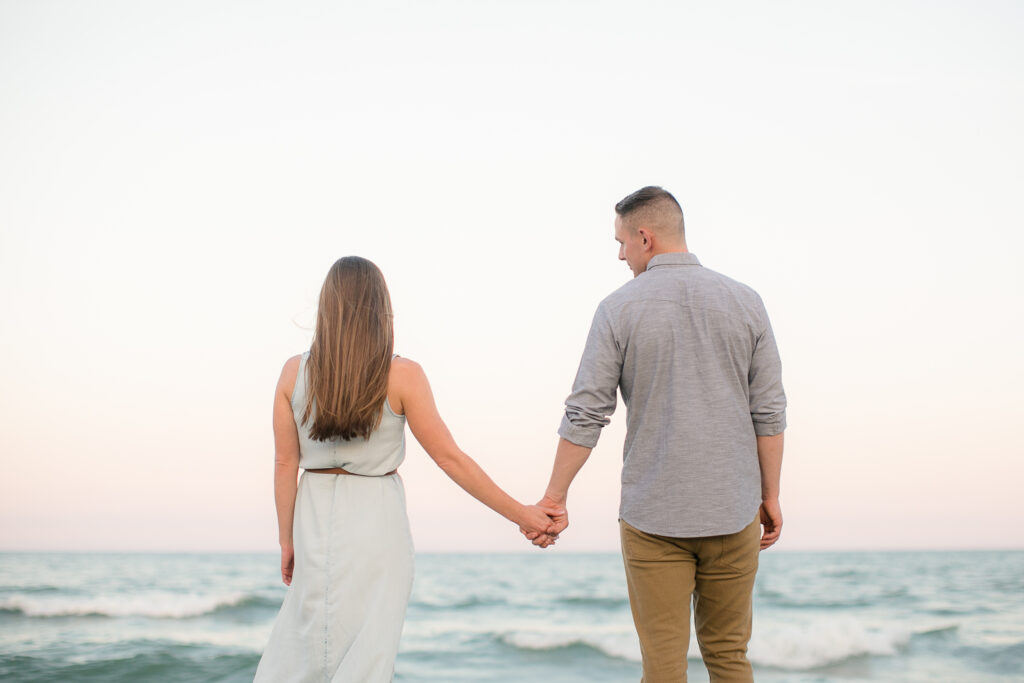 Engaged couple looks out over Wrightsville Beach NC during their engagement session photography.