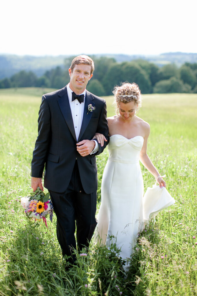 Bride and groom walk through field in East Burke VT.