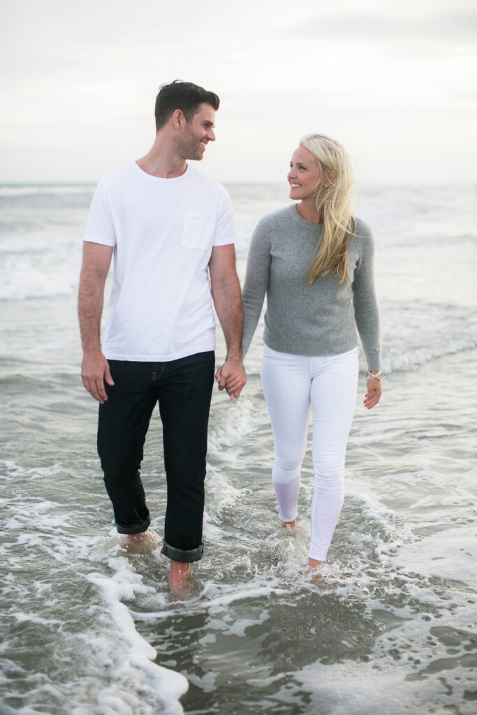 Engaged couple walks in water during engagement session photography on Wrightsville Beach NC.