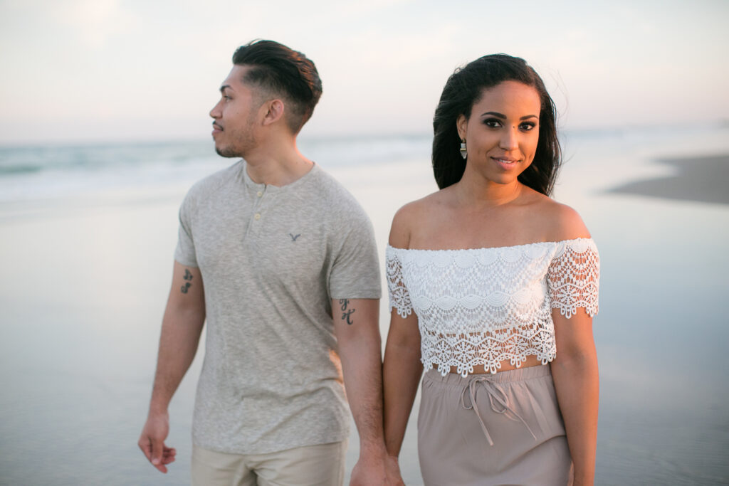 engaged couple walks up wrightsville beach during engagement session photos.