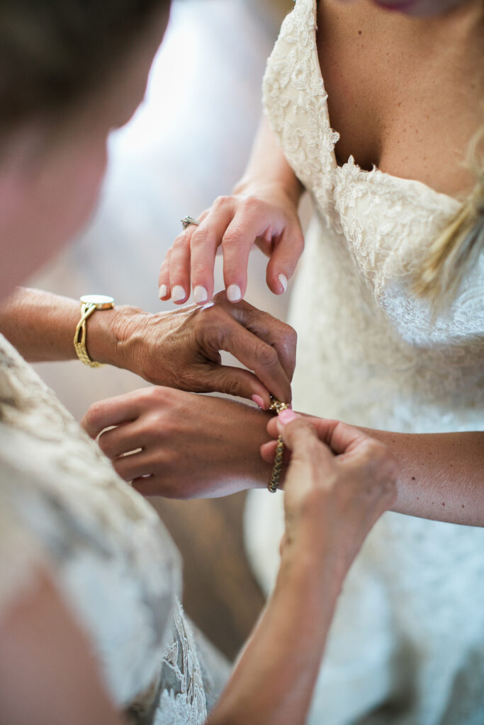 A mother helps the bride put on a bracelet at her wedding in Wilmington NC.