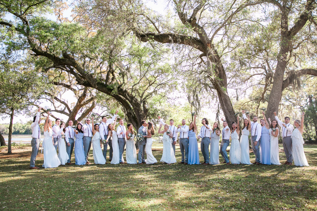 The wedding party stands under a tree at Airlie Gardens