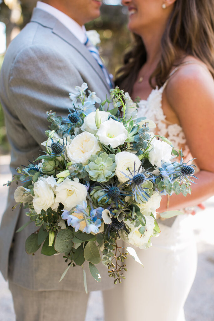 Bride and groom hug with the bouquet in focus during this Airlie Garden wedding.